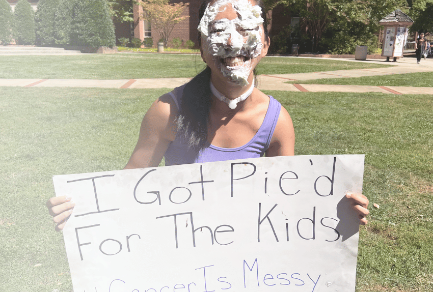 A college student holding a sign that says 