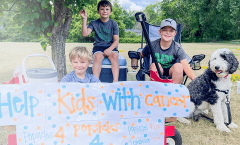 Three kids and their dog with a sign that says 