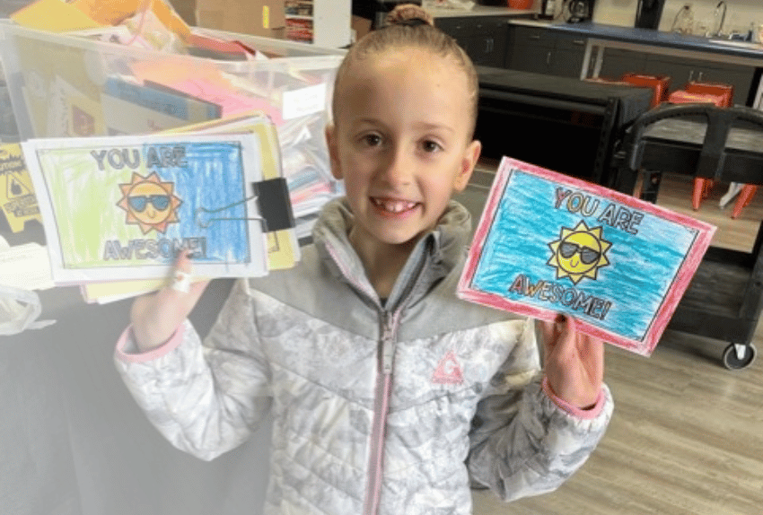 All-Star Kylie's sister holding up two Letters of Encouragement that are brightly colored.