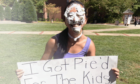 A college student holding a sign that says 