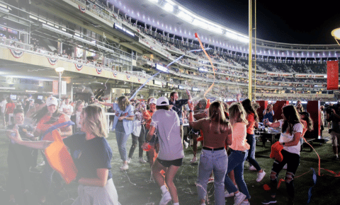 A large group of people at the Minnesota Twins game shooting each other will silly string as a part of a fundraiser for kids with cancer.