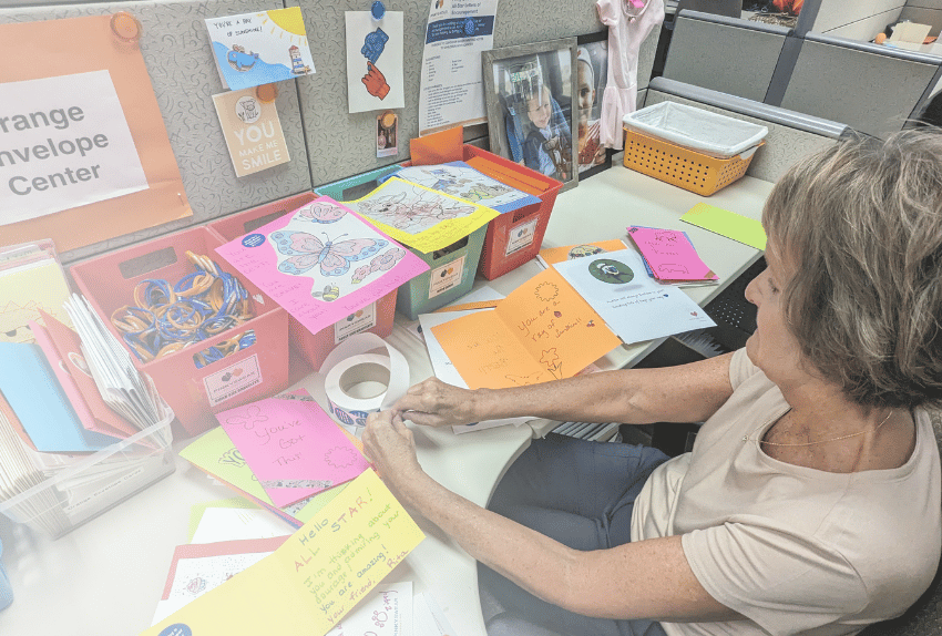 A volunteer putting stickers on cards for kids with cancer at the Pinky Swear office