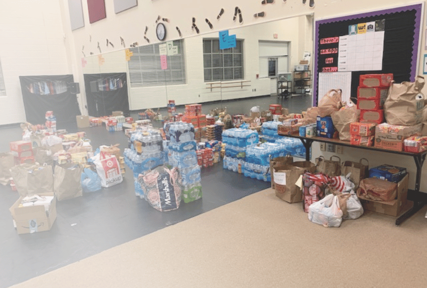 Piles and piles of boxes with food and water bottles in a large room with a mirror for the Pinky Swear Foundation pantries.